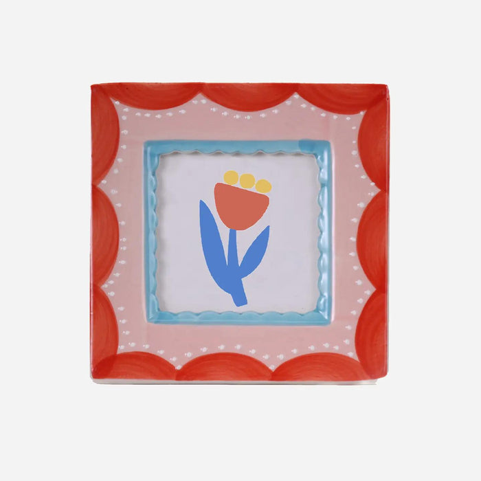 “Square hand-painted ceramic photo frame featuring red scalloped patterns on a white base.”
“Close-up of a red scallop ceramic frame displaying a small photo on a neutral background.”
“Hand-painted red and white scallop photo frame styled on a desk beside flowers and candles.”
