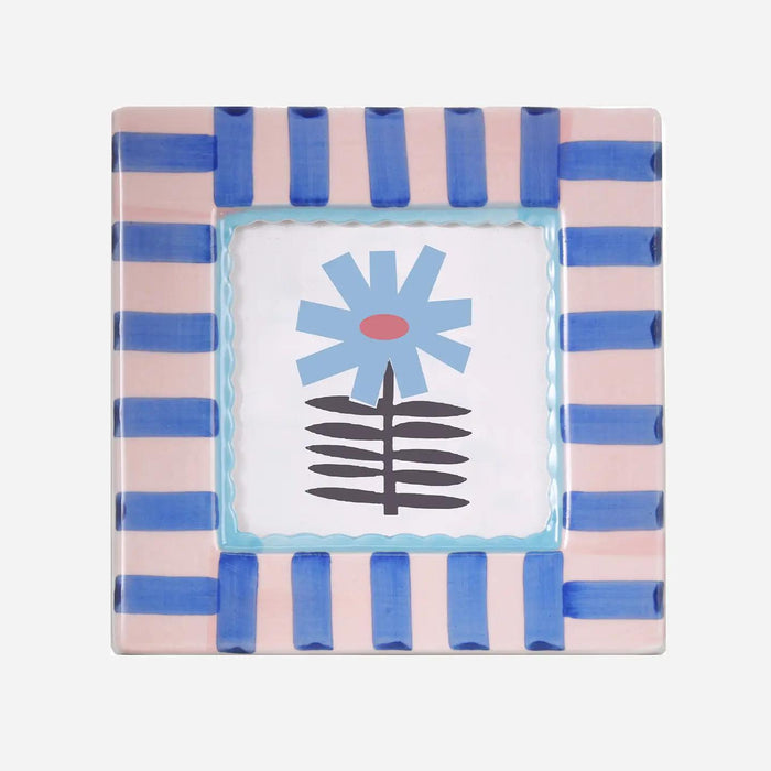 Square hand-painted ceramic photo frame with soft blue stripes on a white base.”

“Close-up of a blue-striped ceramic frame holding a small photo on a wooden shelf.”

“Hand-painted blue and white ceramic frame styled beside flowers and candles.”
