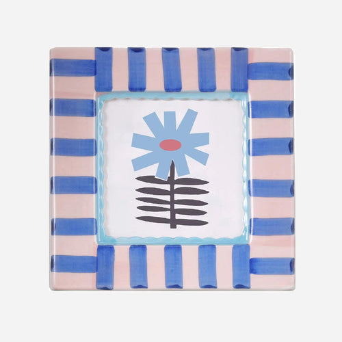 Square hand-painted ceramic photo frame with soft blue stripes on a white base.”

“Close-up of a blue-striped ceramic frame holding a small photo on a wooden shelf.”

“Hand-painted blue and white ceramic frame styled beside flowers and candles.”
