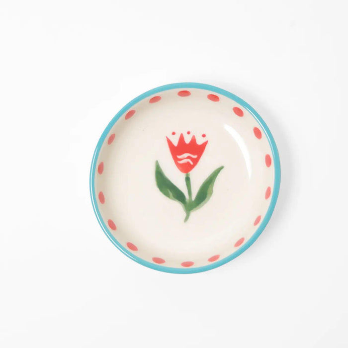 “Small hand-painted ceramic bowl with red flower design, blue rim, and red dots on white background.”

“Close-up of mini stoneware bowl holding gold jewelry, decorated with red flowers.”

“Petite hand-painted red floral bowl styled beside pink petals and a cup of tea.”