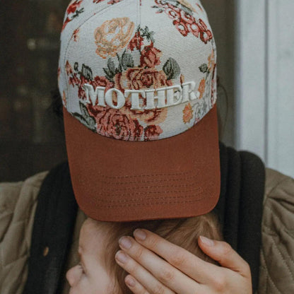 “Embroidered Floral Mother Hat” – Hat on a rustic wood table with flowers and sunglasses

“Maroon Bill Mother Hat” – Close-up of embroidery and floral pattern with soft natural lighting