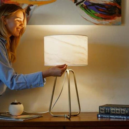 Small modern stylish desk lamp with marble-patterned shade and bronze base on wooden table