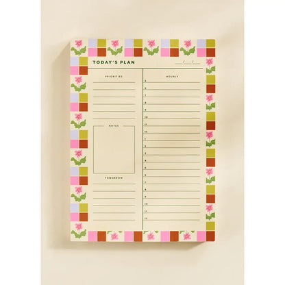 “Floral Checkered Planner Pad” – Close-up of floral-bordered daily planner with pen and coffee mug

“Pretty & Productive Desk Setup” – Notepad styled on a workspace with colorful stationery